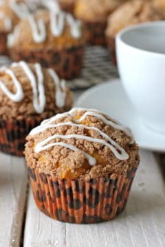A baked pumpkin streusel muffin topped with drizzled vanilla glaze.